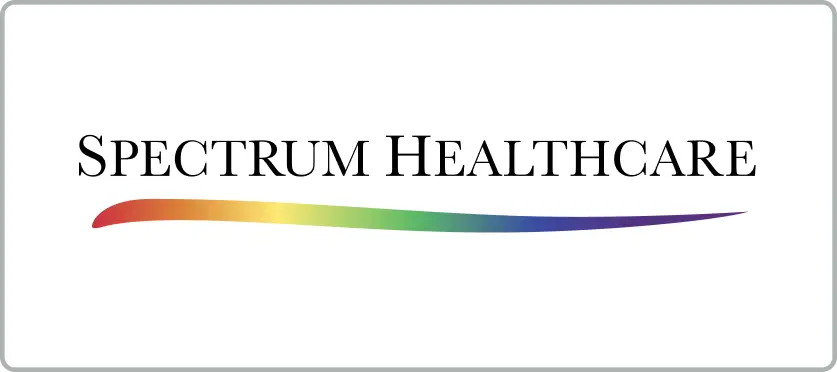 Logo for Spectrum Healthcare. The text SPECTRUM HEALTHCARE appears in black uppercase letters above a curved line that fades from red to purple, displaying a rainbow gradient. The background is white with rounded grey borders.
