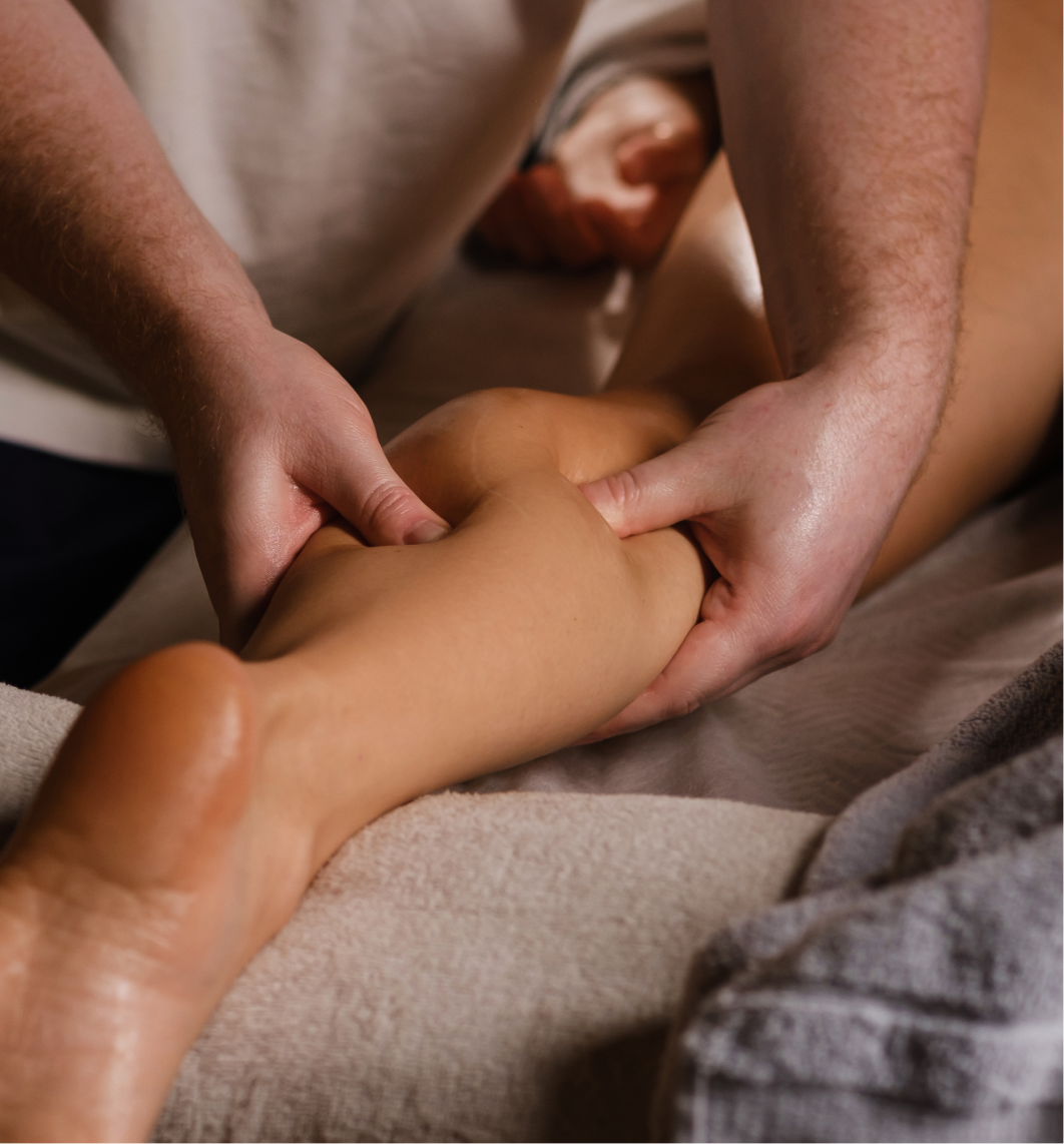 Close-up of a person receiving a calf massage while lying face down on a massage table. Hands gently knead the lower leg muscles, reflecting techniques highlighted in case studies. A towel is visible, adding to the relaxing, therapeutic atmosphere.